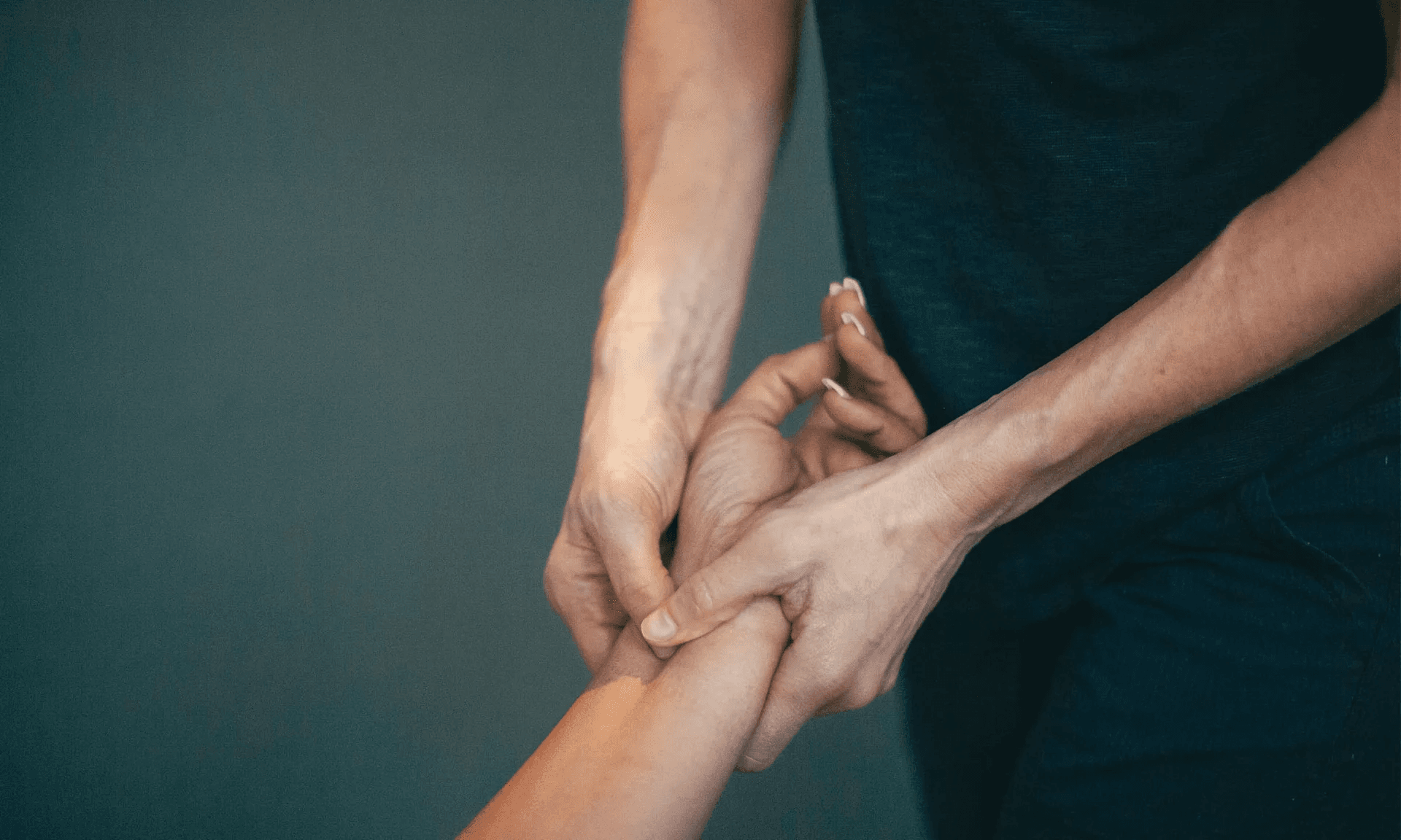 A therapist holding a patient's forearm with both hands, pressing a point near the wrist
