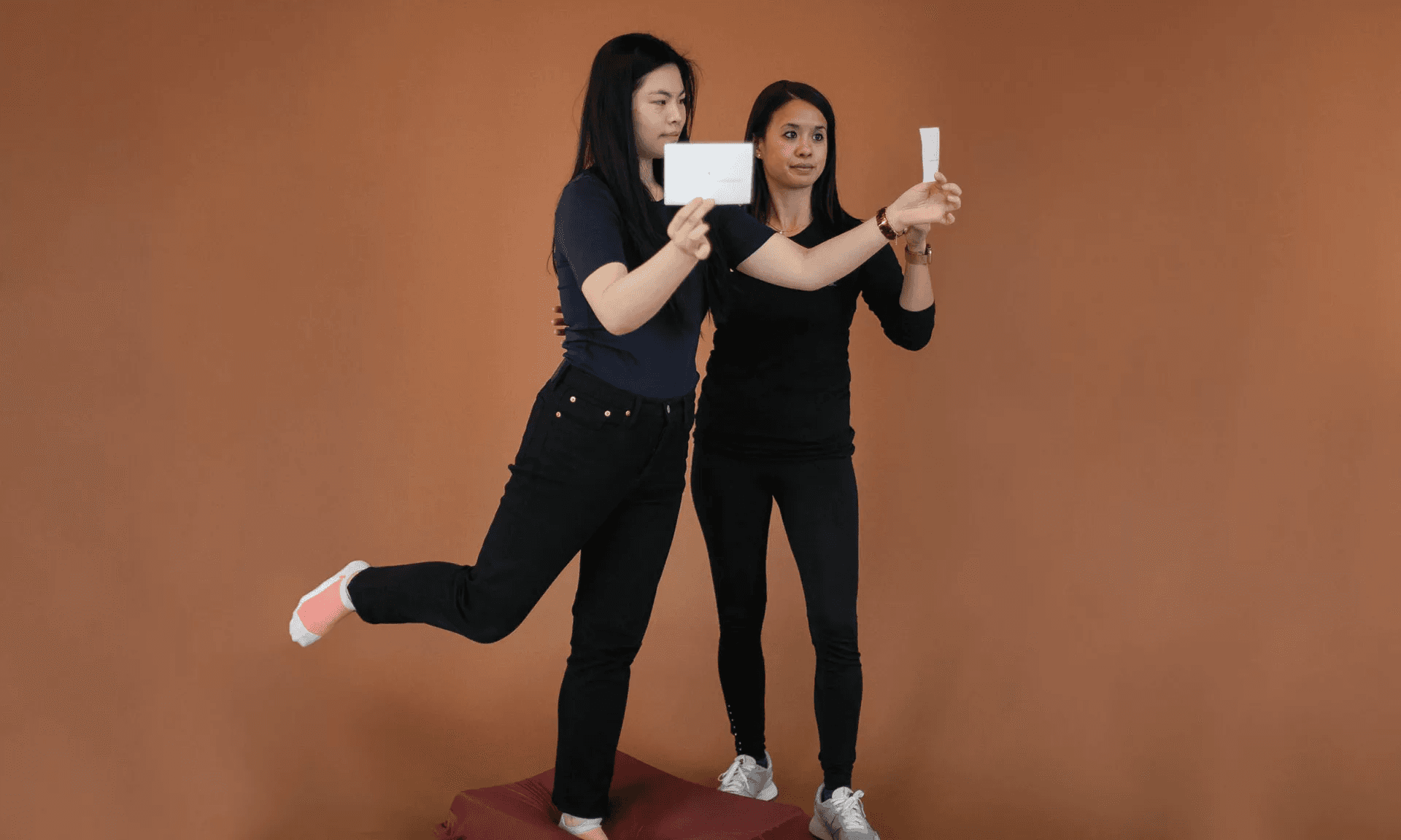 A therapist steadying a patient balancing on one leg on a foam pad during a gaze-stability exercise