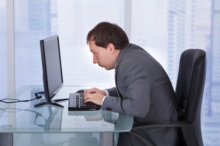 Hunched shoulders and forward head positioning due to poor desk posture.