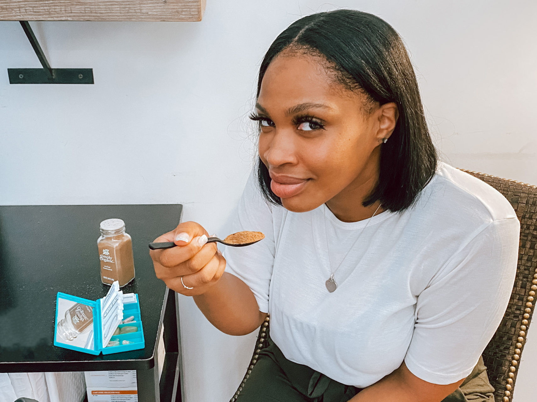 Shiann from Physio Logic NYC in Brooklyn, NY holding up a spoonful of cinnamon with her supplements to demonstrate the health benefits of cinnamon.