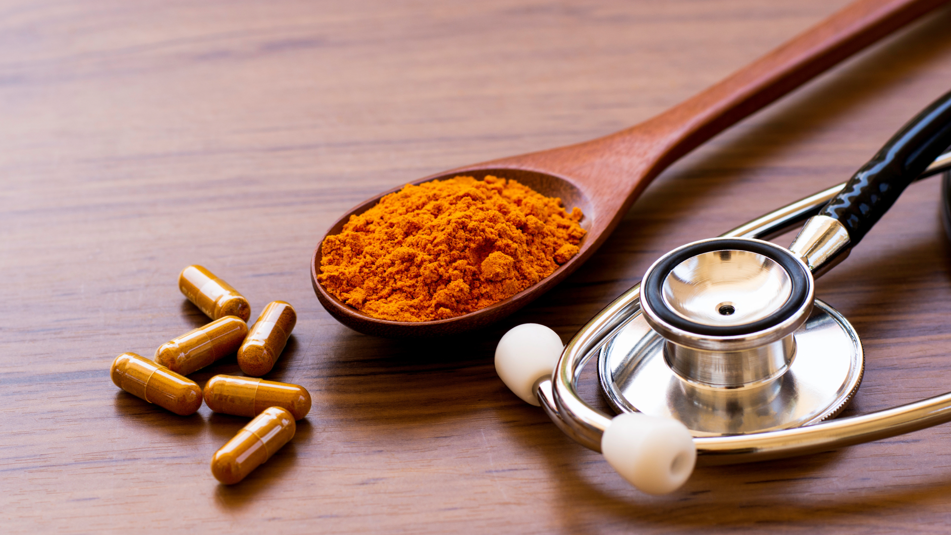 Turmeric in it's powdered form and supplement form with a stethoscope representing the health benefits of turmeric.