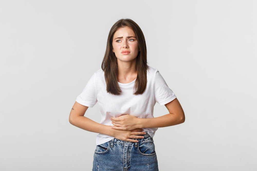 Young woman holding stomach in discomfort, illustrating symptoms of IBS